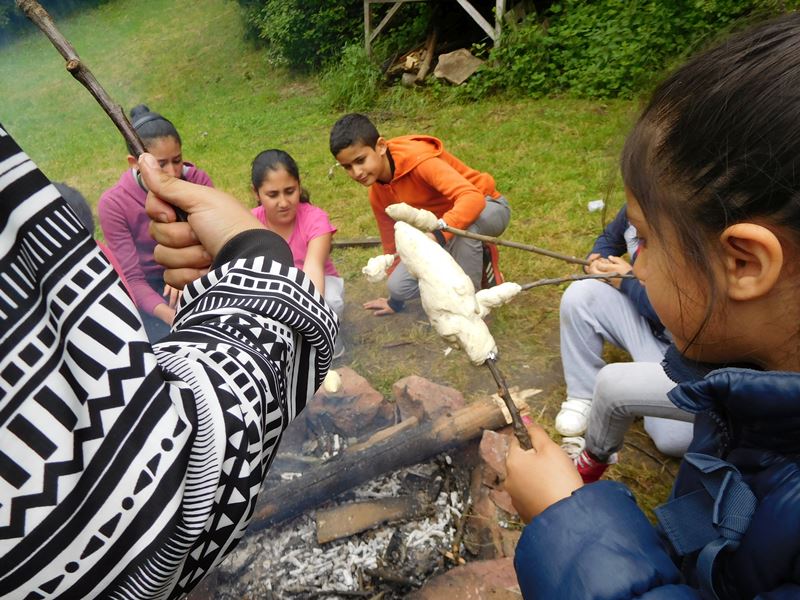 Kinder warten am Lagerfeuer mit ihrem Stockbrot