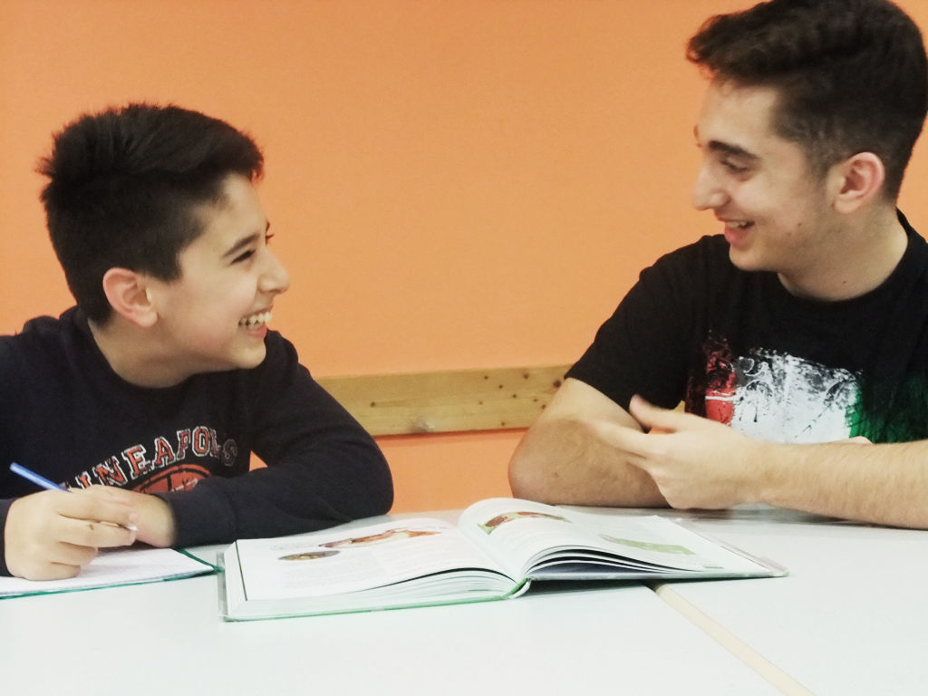 Zwei Jugendliche lernen miteinander, sie haben Spaß dabei.