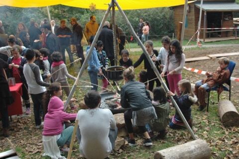 Kinder halten Stöcke ins Feuer und backen Stockbrot