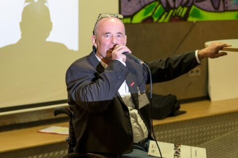 Ein Mann spricht ins Mikrofon und gestikuliert.