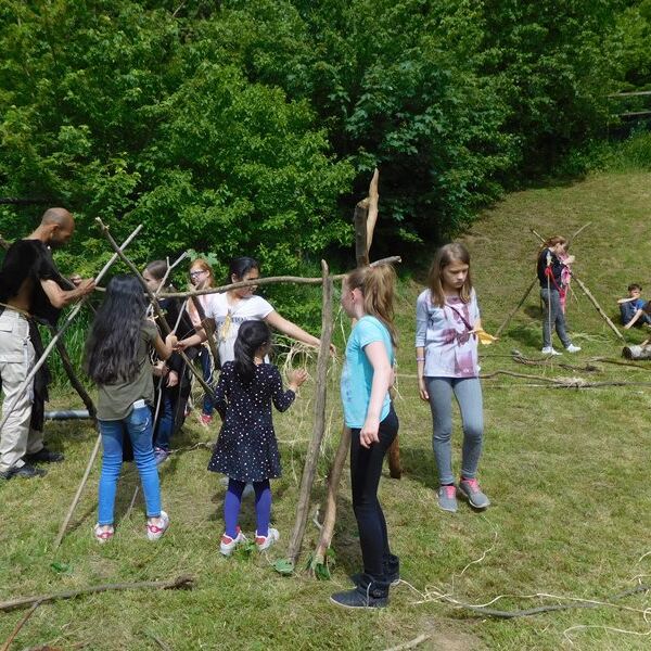 Kinder bauen die geripper der Laubhütten.